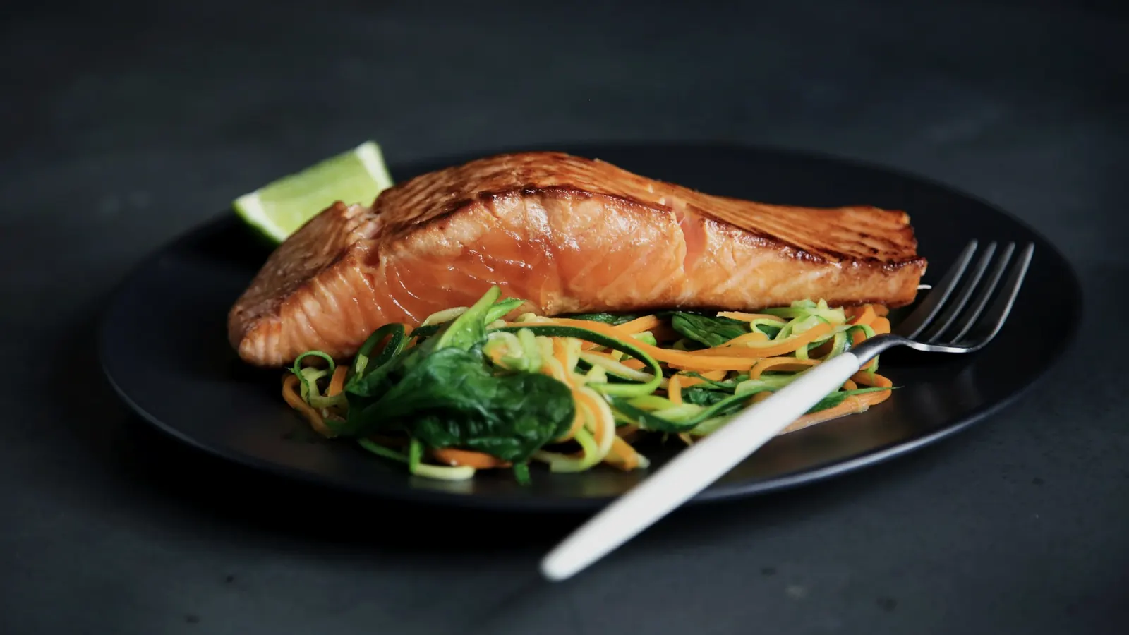 Plato de salmón con verduras sobre una mesa oscura